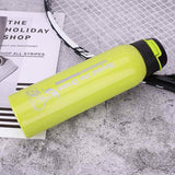 Petra store bright yellow Bike Water Bottle with secure black cap placed next to a tennis racket