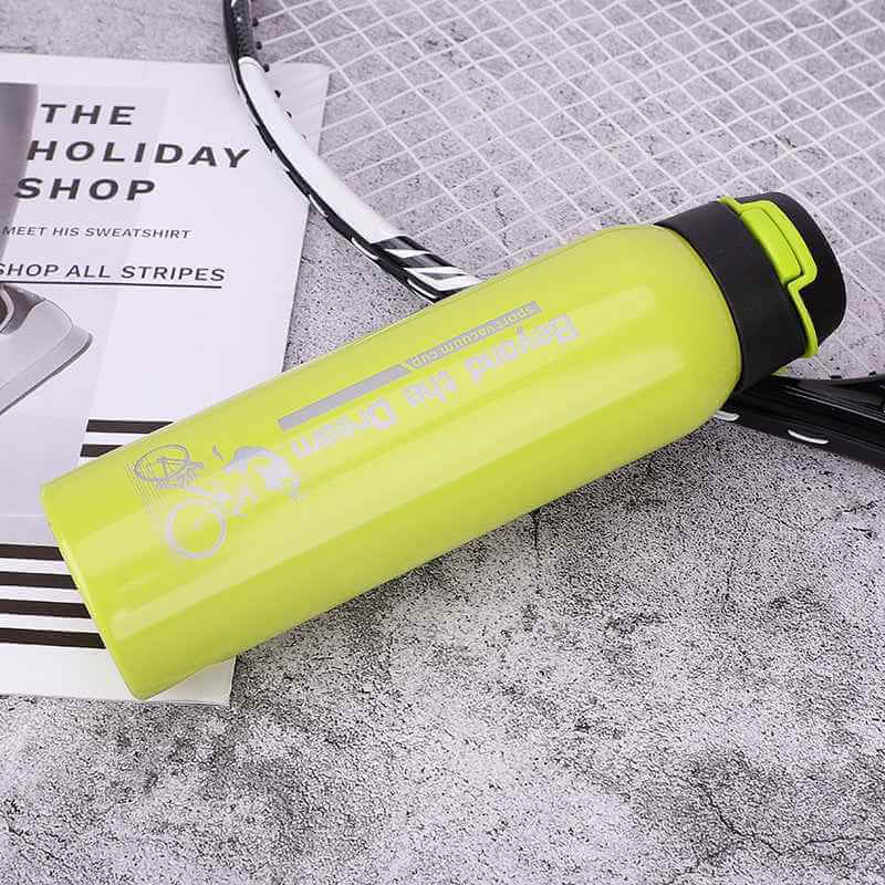 Petra store bright yellow Bike Water Bottle with secure black cap placed next to a tennis racket