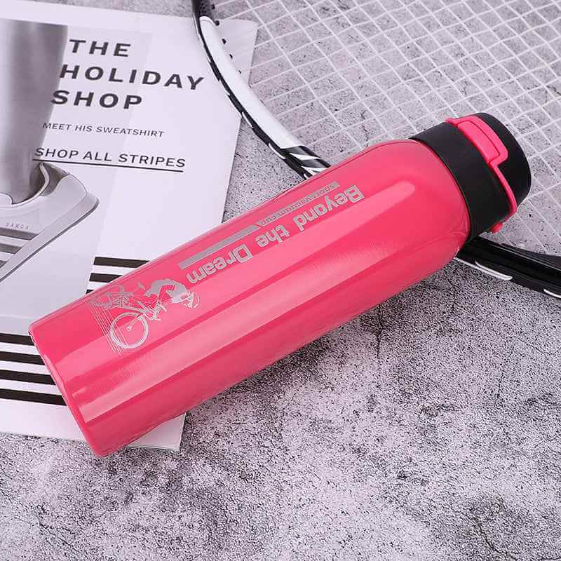 Petra store bright pink Bike Water Bottle with secure black lid on textured surface next to a tennis racket