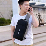 Young man wearing a black and gray chest bag from Petra store while using earphones outdoors