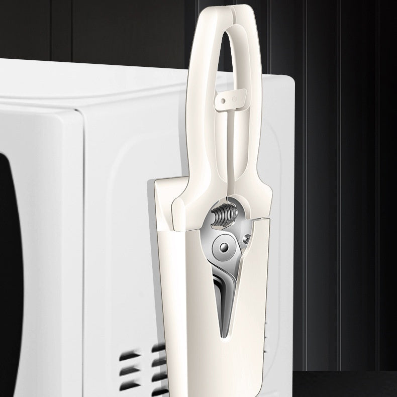 Petra store white compact kitchen scissors with safety sheath stored on microwave side holder