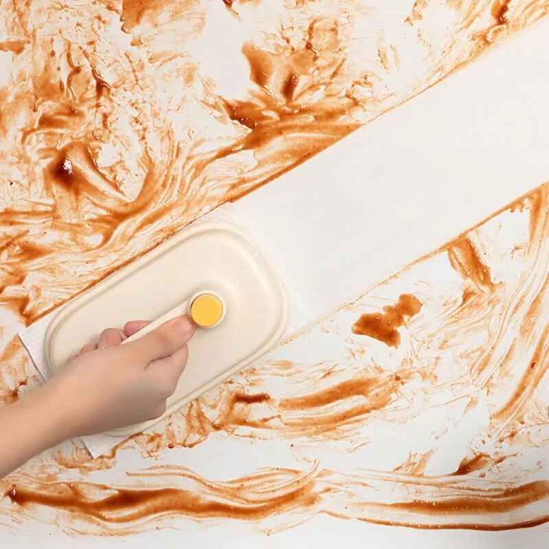 Hand using Cleaning Magic Brush from Petra store to clean sticky brown residue on white surface