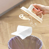 Hand holding a beige Cleaning Magic Brush from Petra store over a trash can with a white cloth