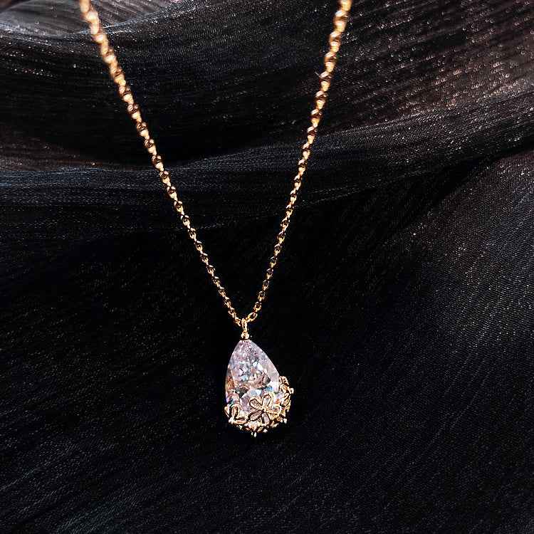 Gold chain Crystal Water Drop Pendant Necklace with floral design on black fabric background