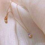 Petra store Crystal Water Drop Pendant Necklace with gold chain on soft fabric background