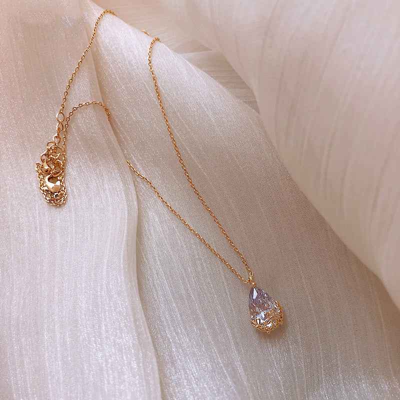 Petra store Crystal Water Drop Pendant Necklace with gold chain on soft fabric background