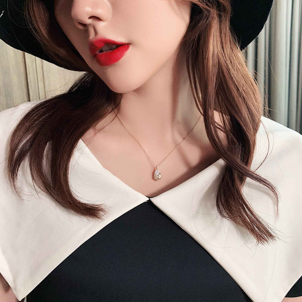 Woman wearing Crystal Water Drop Pendant Necklace with red lipstick and black and white top