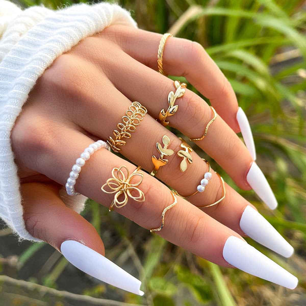 Petra store gold Flower Ring Set featuring delicate floral and pearl designs on a hand with long white nails