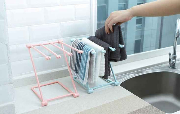 Foldable Dishcloth Shelf in pink and blue colors holding hanging dishcloths by kitchen sink