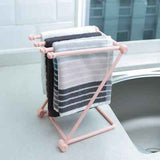 Petra store Foldable Dishcloth Shelf in pink holding multiple dishcloths on a kitchen counter near sink