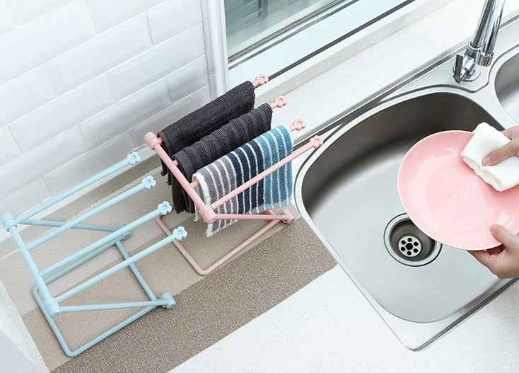 Petra store foldable dishcloth shelf in pink and blue holding drying towels beside kitchen sink