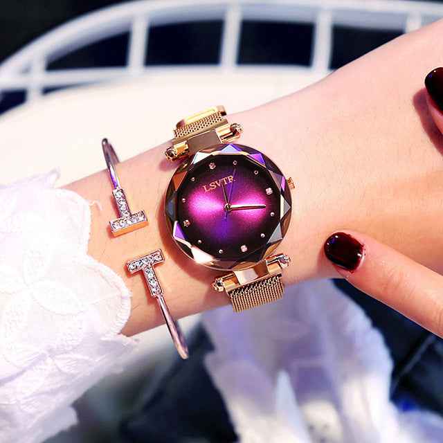 Petra store Rose Gold Watch with faceted purple sunray dial and mesh band on wrist with bangles