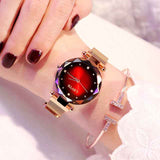Petra store Rose Gold Watch with faceted red dial and mesh band on female wrist with bracelet