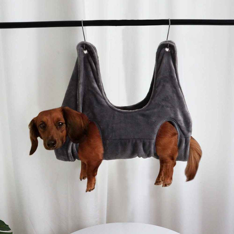 Brown dachshund dog secured in gray Pet Grooming Hammock hanging from rod for easy grooming