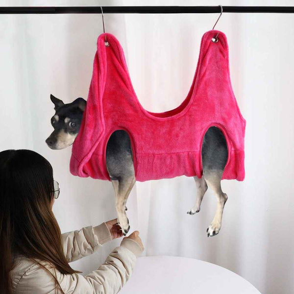 Pet grooming hammock in bright pink soft fabric holding small dog for easy grooming