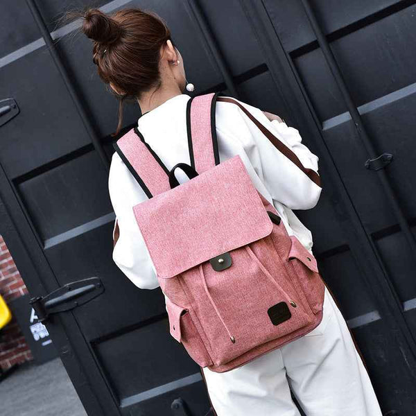 Pink travel backpack for teenage girls with flap and side pockets worn by girl in white outfit