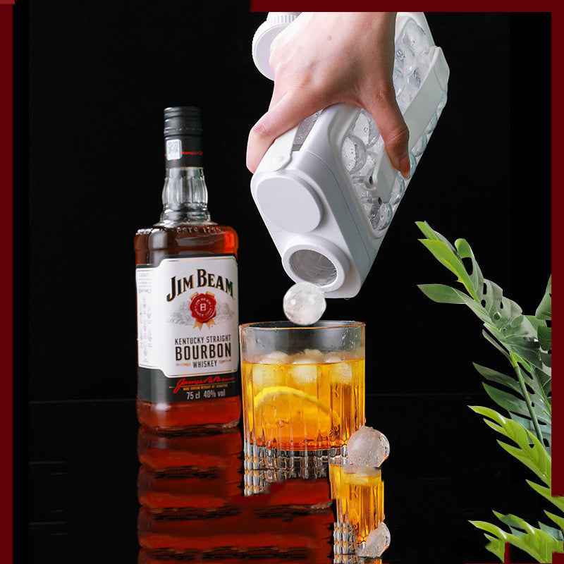 Petra store portable ice ball maker kettle pouring clear ice spheres into whiskey glass next to Jim Beam bottle