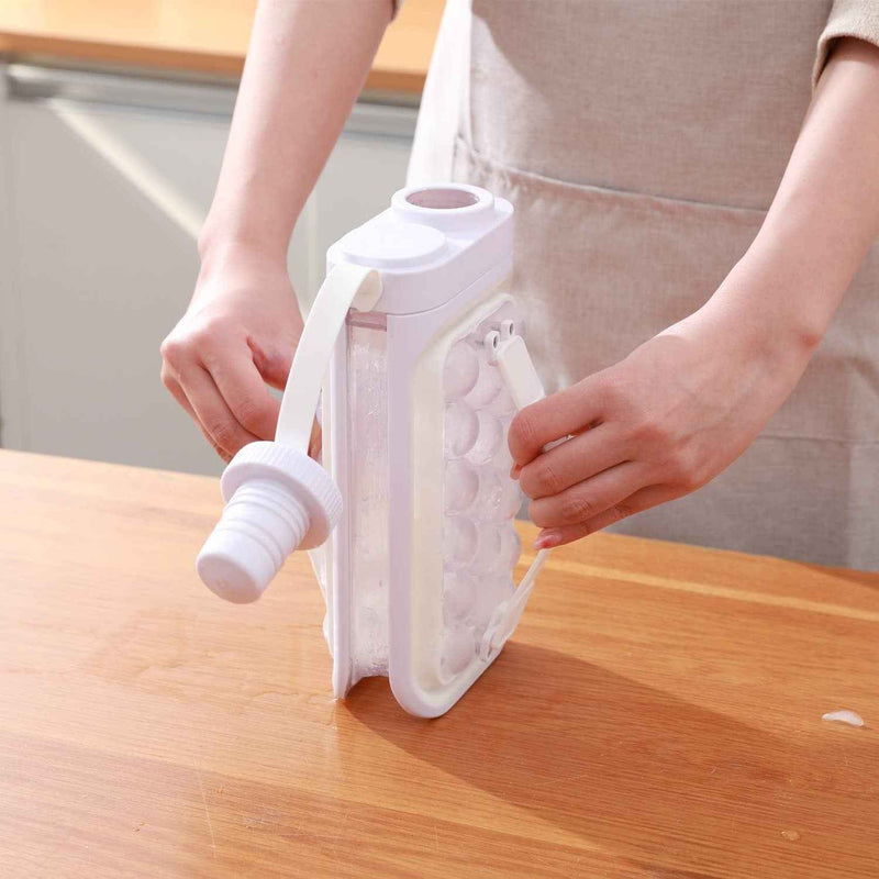 Petra store portable ice ball maker kettle held by hands on wooden countertop showing ice spheres
