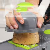Petra store vegetable cutter with hand guard slicing potato on gray and green mandoline slicer